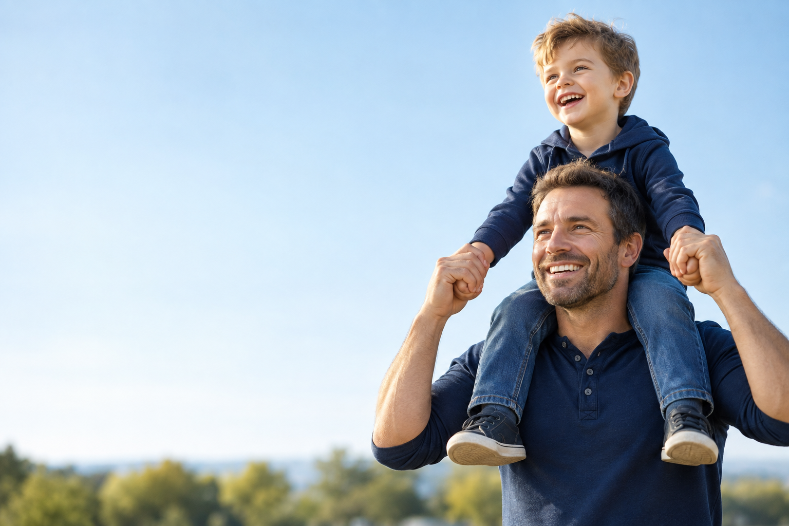 A smiling father carrying his young son on his shoulders